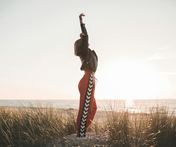 Person stretching peacefully outdoors during sunset.
